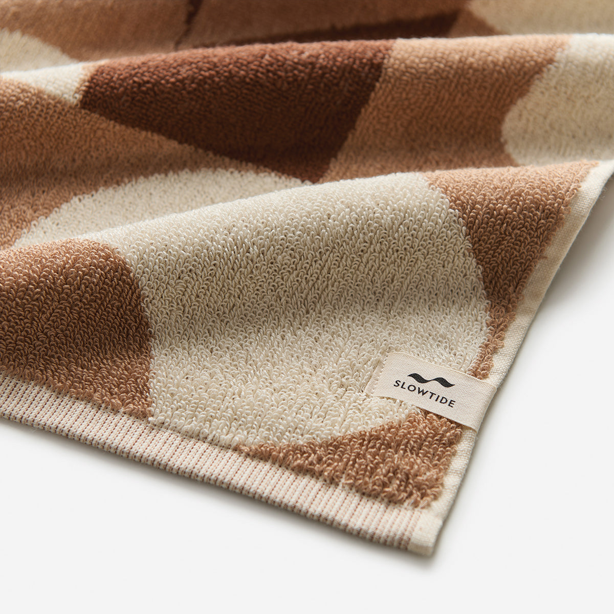 Cotton beach towel with a brown and cream geometric pattern for sand resistance.