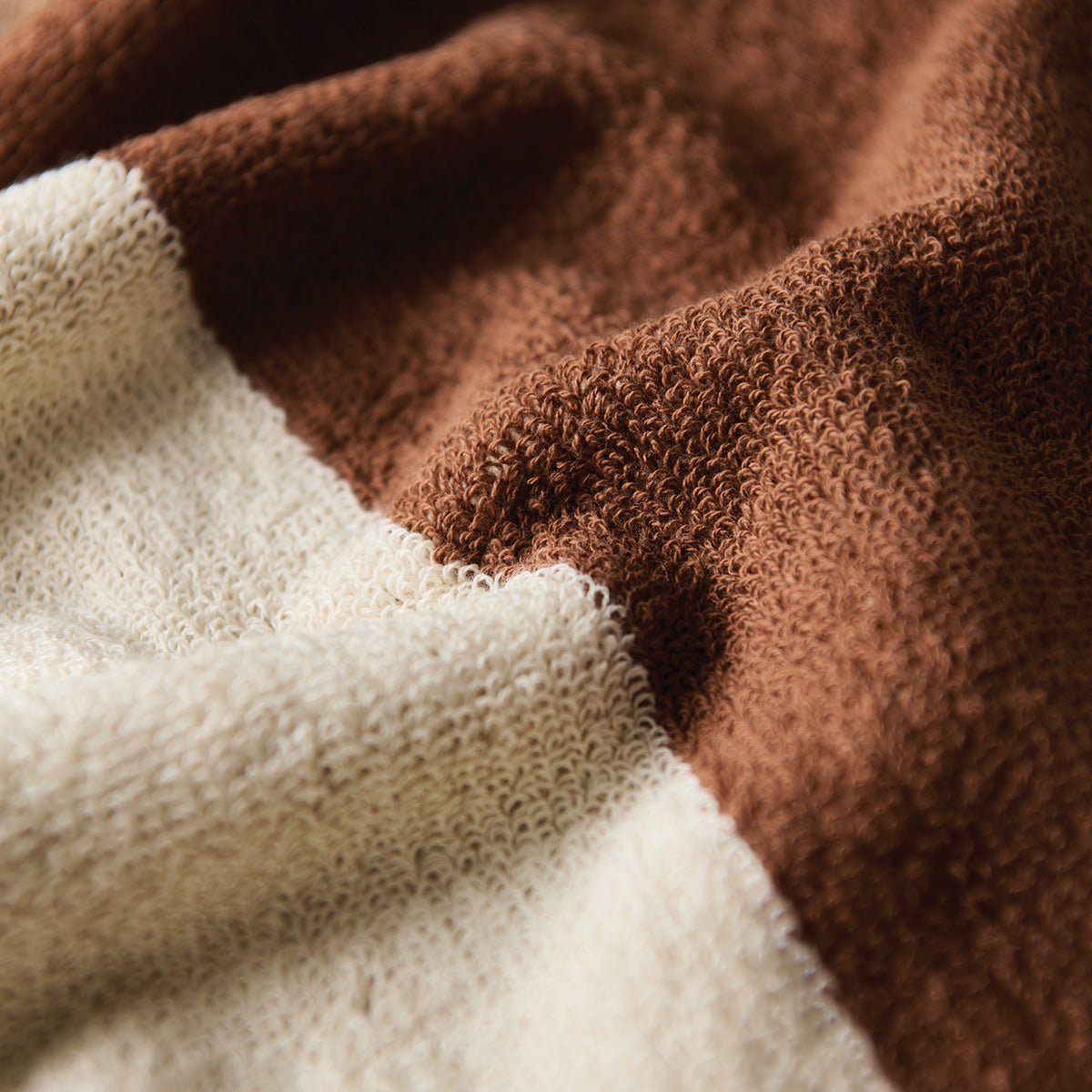 Oversized terry cloth towel in brown and cream color-blocked design.
