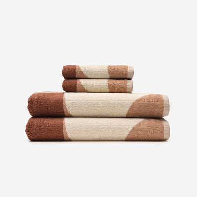 Cotton bath and hand towel stack featuring a brown and cream geometric pattern.