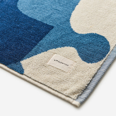 Cotton bath mat in a blue and cream abstract pattern.