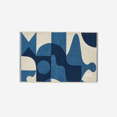 Cotton bath mat with blue and white geometric pattern.