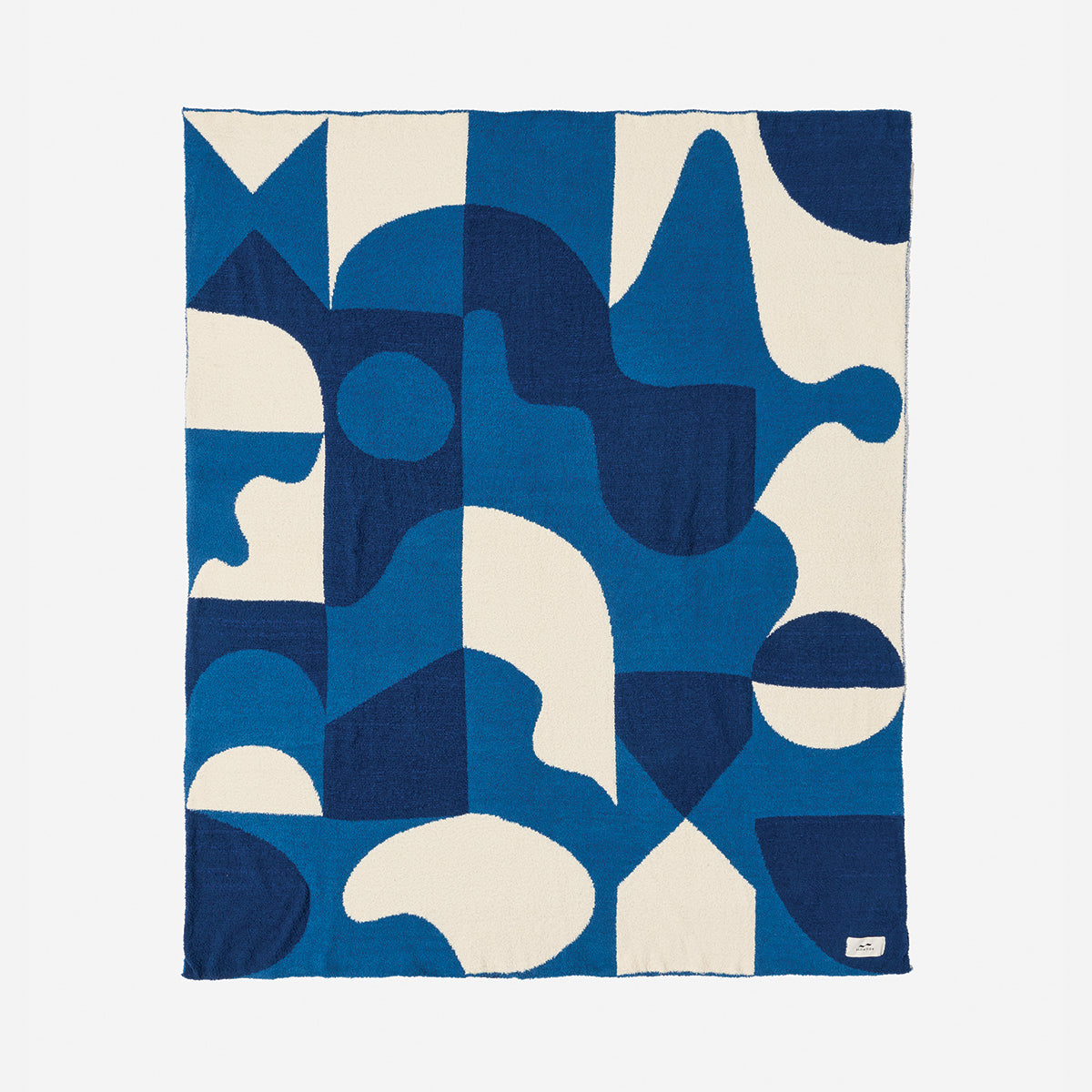 Reversible knit throw blanket in plush recycled fabric with a blue and white geometric pattern.