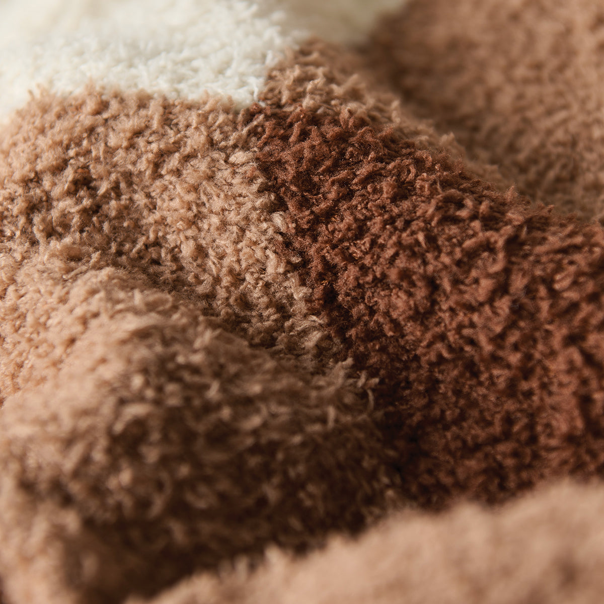 Plush blanket in fuzzy recycled polyester with brown and white color-blocked stripes.