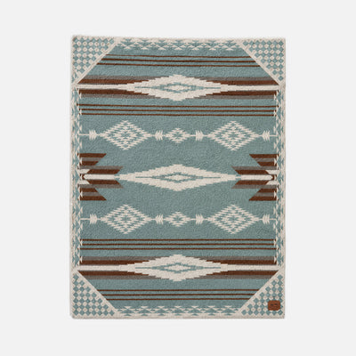 Rug with blue and brown diamond geometric pattern, suitable for layering under throws.