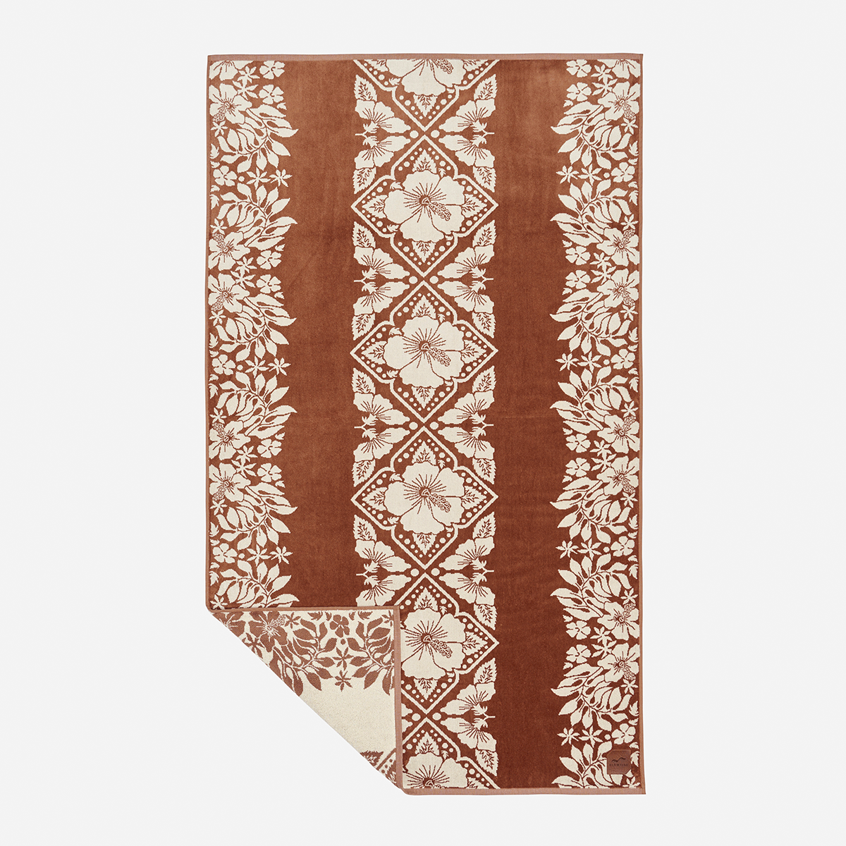 Jacquard beach towel with brown and beige floral pattern, corner folded to show design.