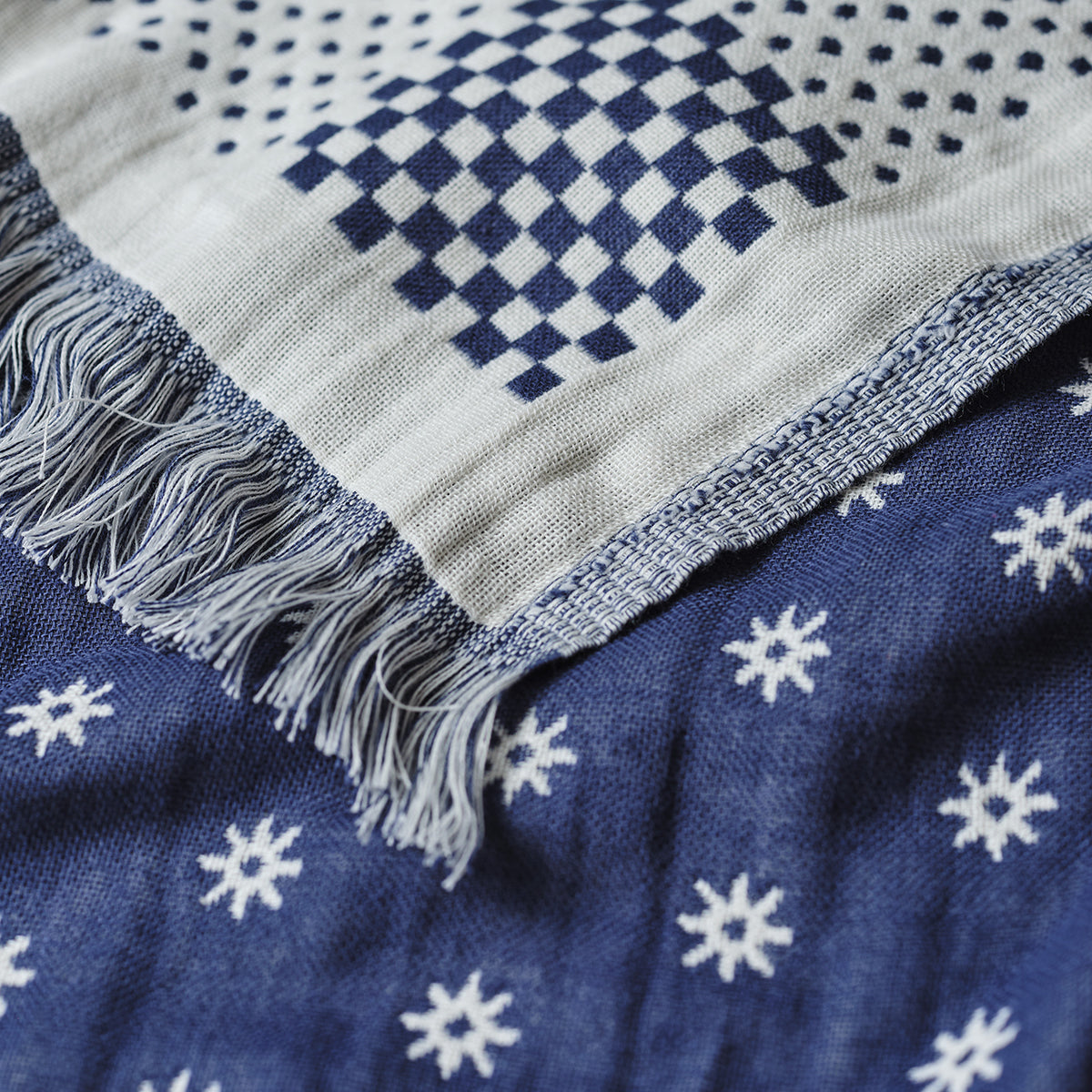 Turkish towel with blue and white geometric patterns and fringed edges, lightweight cotton.