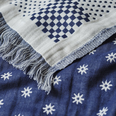Turkish towel with blue and white geometric patterns and fringed edges, lightweight cotton.