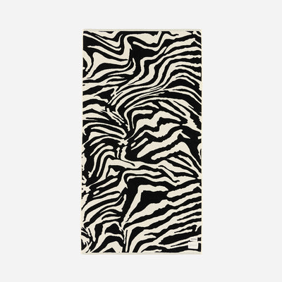 Beach towel with absorbent fabric and black and white zebra stripe pattern on white background.