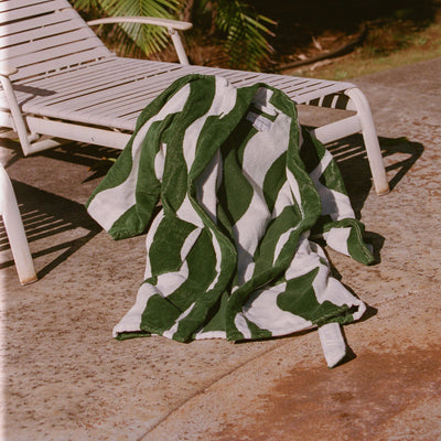 Bathrobe displayed on a white poolside lounge chair in sunlight.