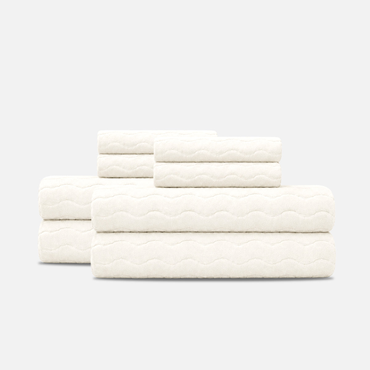 Cotton towels with sculpted wave texture, stacked on a plain surface.