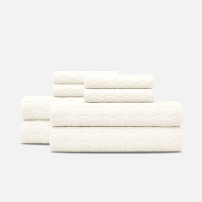 Cotton towels with sculpted wave texture, stacked on a plain surface.