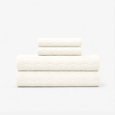 Cotton bath towel set with sculpted wave pattern stacked on plain background.