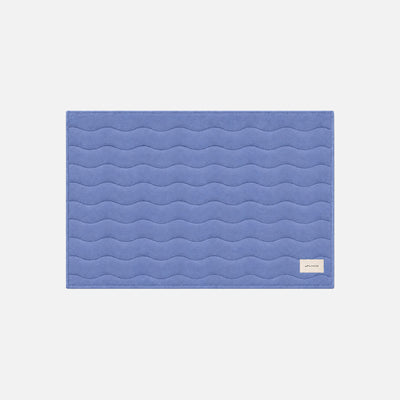 Blue absorbent bath mat with wave pattern and small corner label.