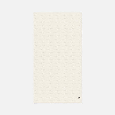 Cotton towel in cream color with plush, wavy texture, shown flat.