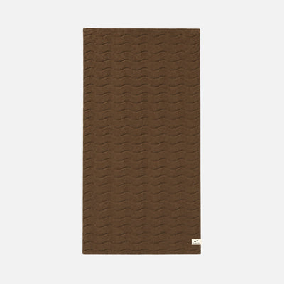Brown bath towel with wavy sculpted texture and small white corner label.