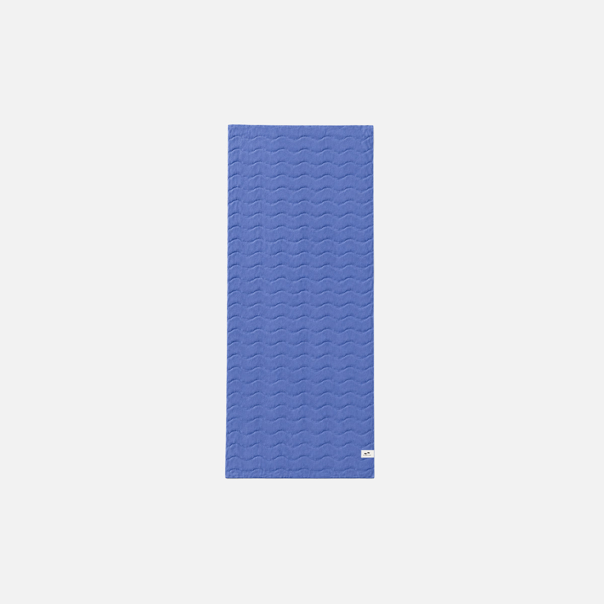 Blue plush cotton towel with wavy stitched pattern on a white background.