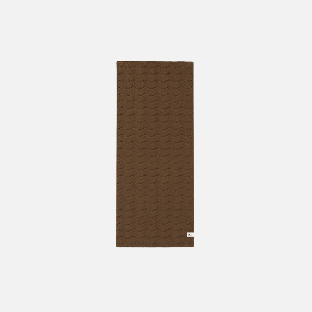 Cotton bathroom towel, brown with rectangular shape and small white tag on bottom right corner.