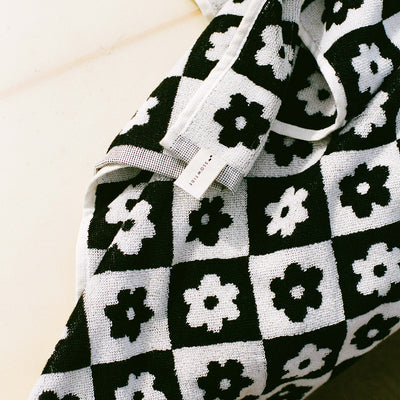 Bath towel, cotton, black and white checkered with flower pattern and small tag attached.