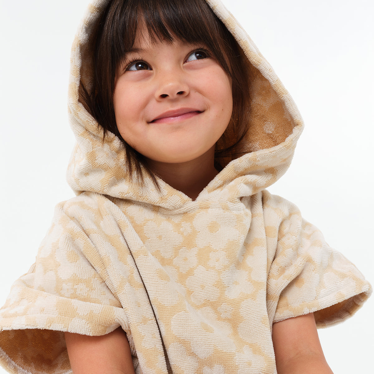 Kids poncho in beige with floral pattern, lightweight fabric.