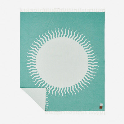 Cotton blanket with white sunburst pattern and fringe edges, corner folded to show detail.