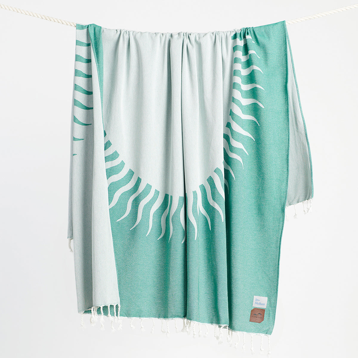 Turkish-style chambray blanket with teal and white sunburst design hanging on rope.