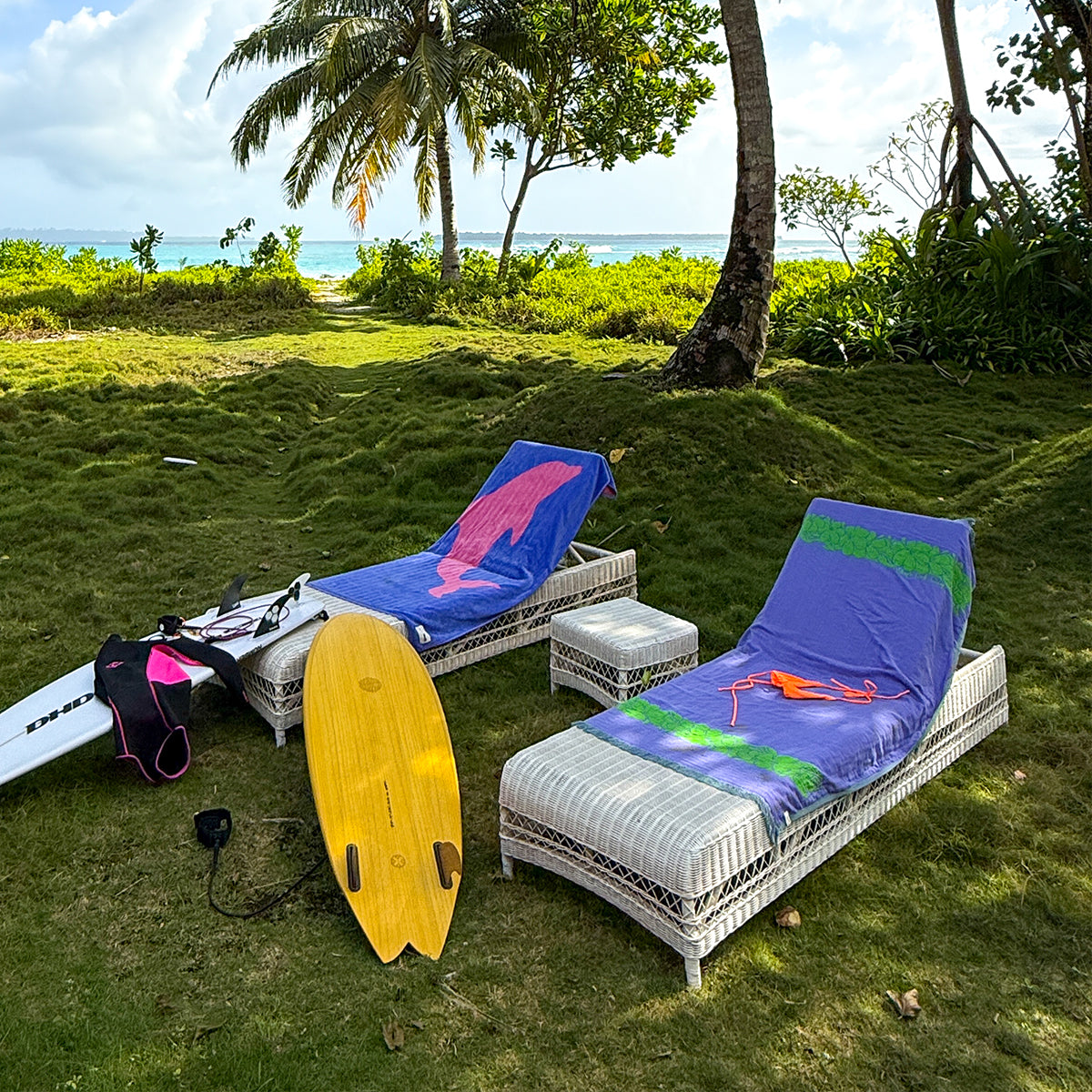 Lounge chairs with fast drying towels, shown on grass by the beach.
