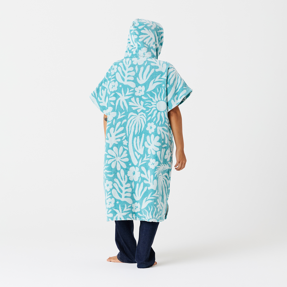 Towel poncho, cotton terry, blue and white floral pattern, on sand.