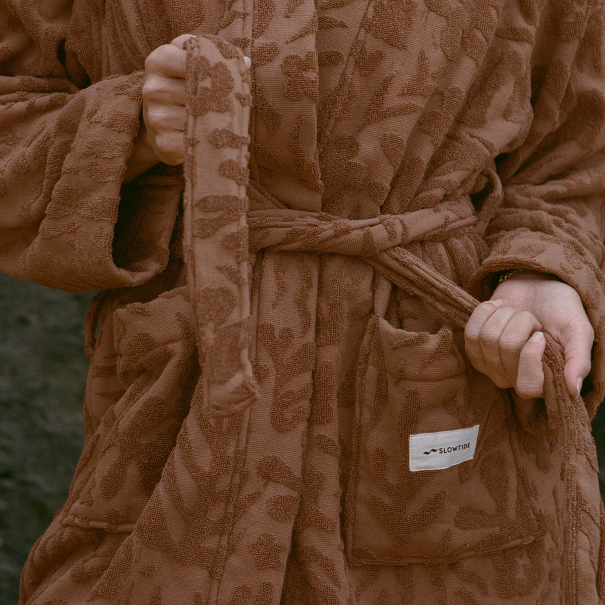 Soft bathrobe with pocket detail, shown being tied at the waist.