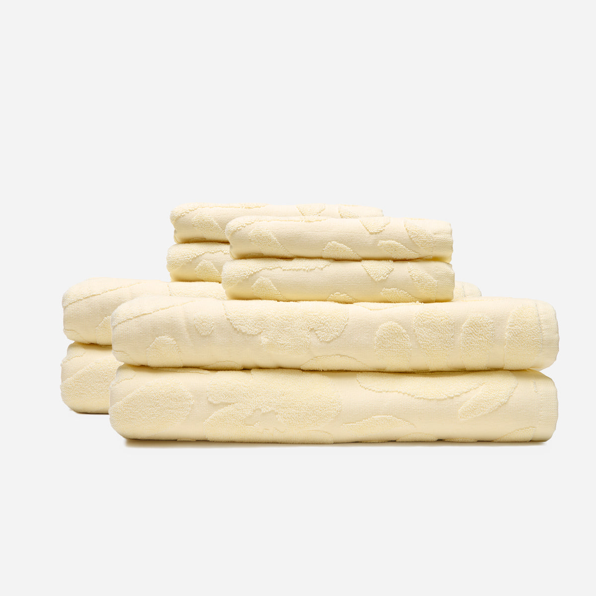 Cream towel set, cotton, neatly stacked on white background.