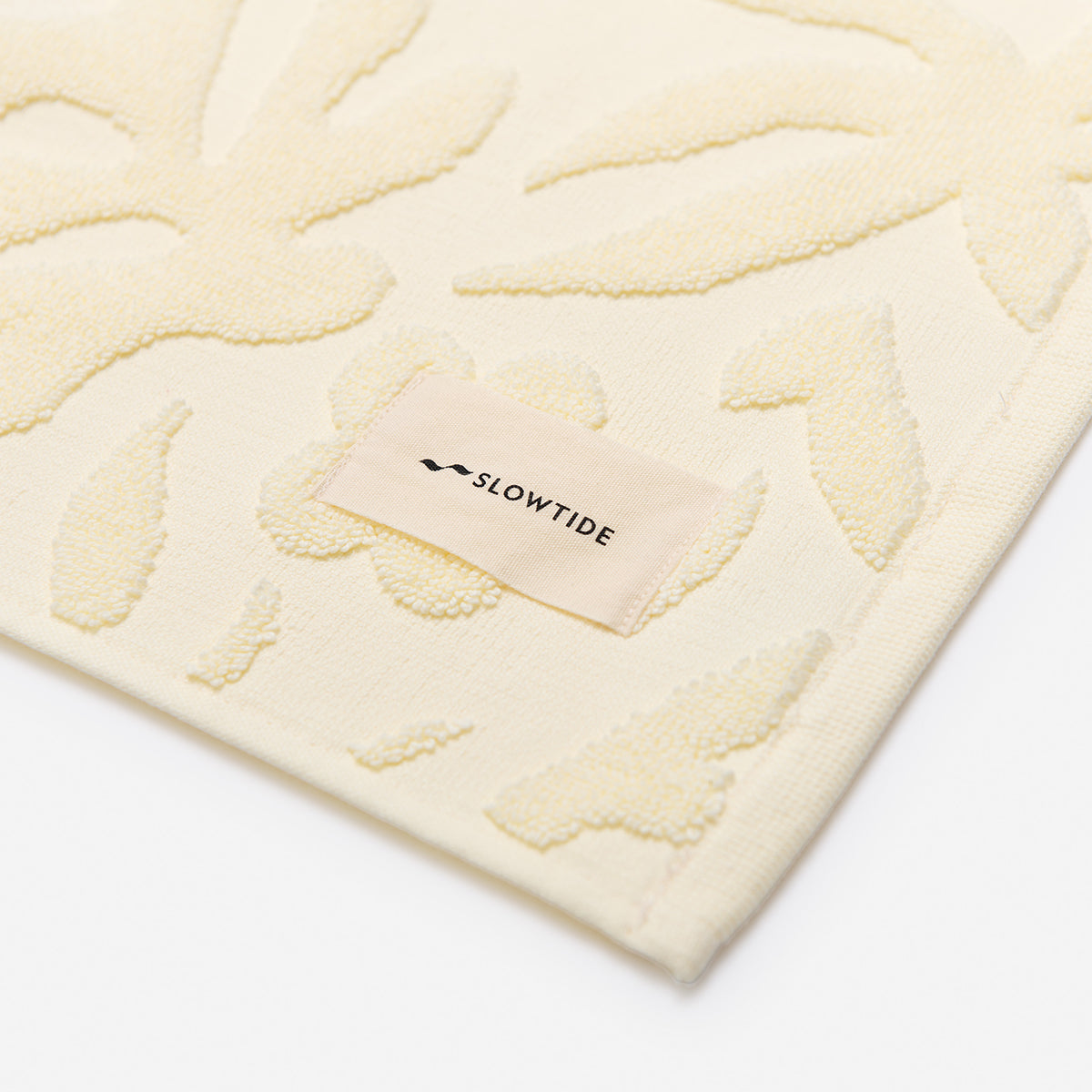 Cream towel with raised floral pattern, soft cotton texture, close-up detail.