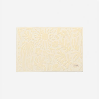 Bath mat, cream color with raised floral pattern, spa-inspired design.