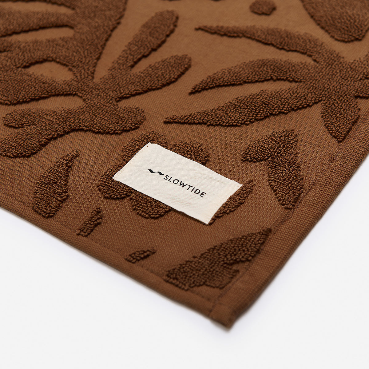 Brown cotton towel, plush and cushioned with white label detail.
