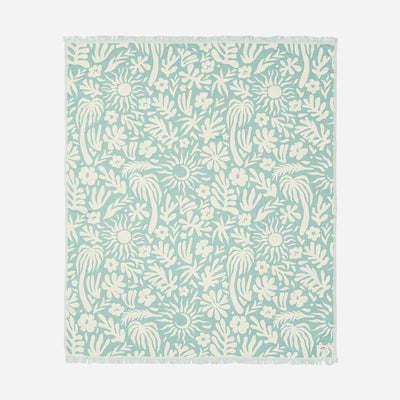 Area rug with pale blue and white organic floral pattern and fringe edges.