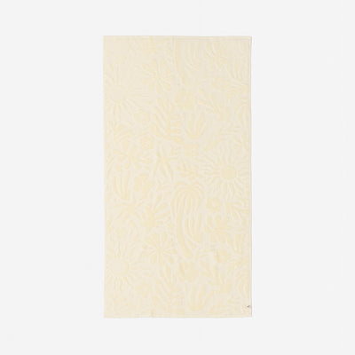 Cotton towel in beige with plush texture and subtle floral pattern for bathroom use.