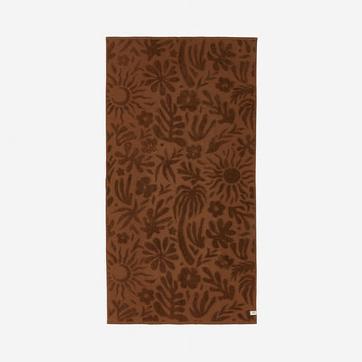 Brown plush bathroom towel with floral and sun print.