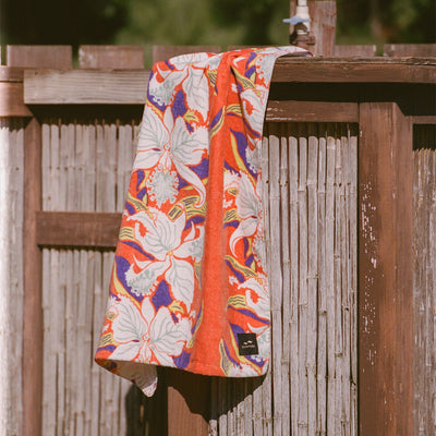Cotton towel with bright color, absorbent, displayed outdoors in sunlight on wooden fence.
