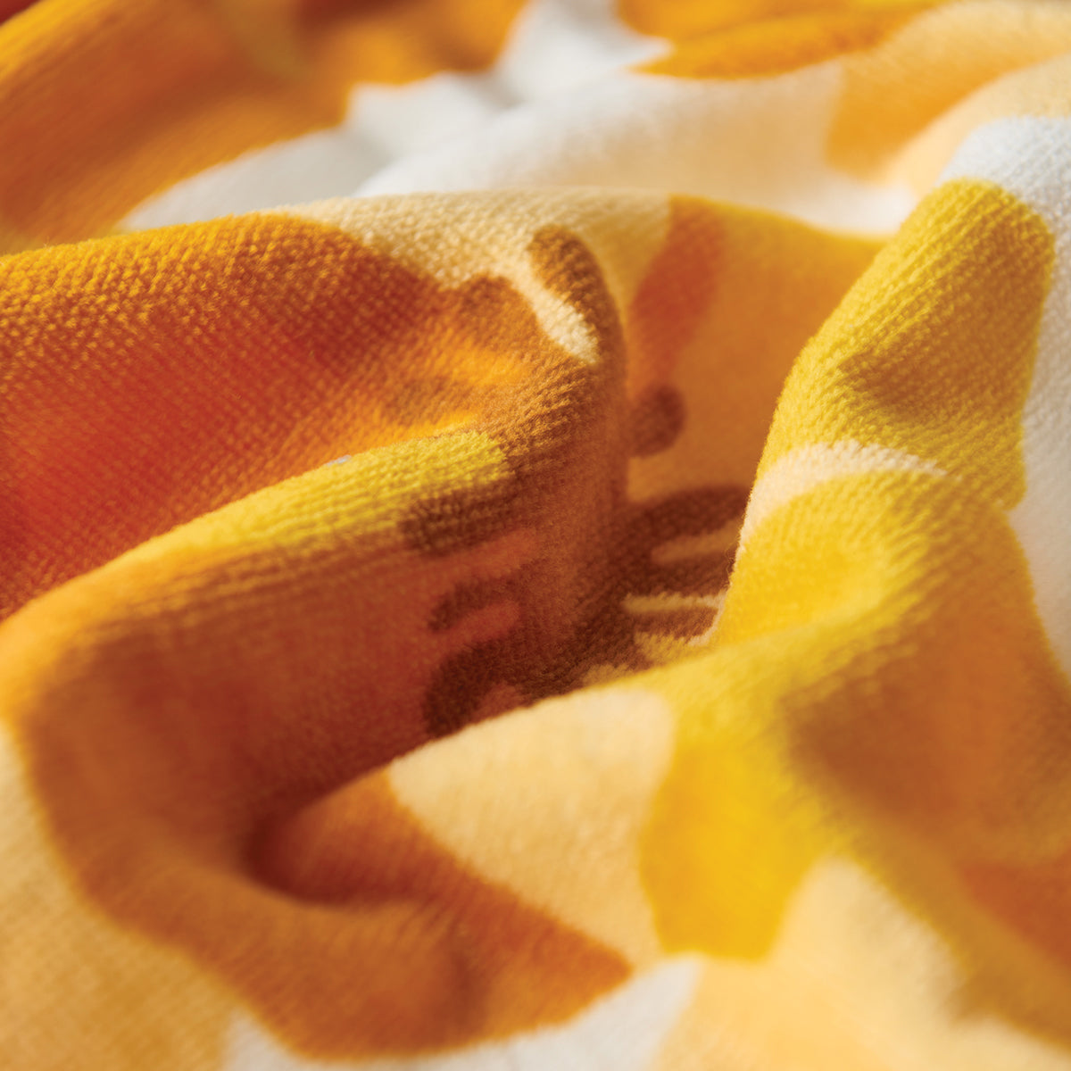 Cotton towel in yellow and orange, soft texture with gentle folds, close-up view.
