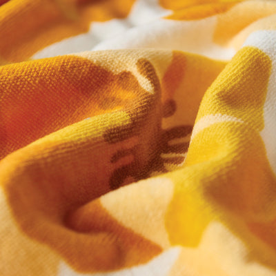 Cotton towel in yellow and orange, soft texture with gentle folds, close-up view.