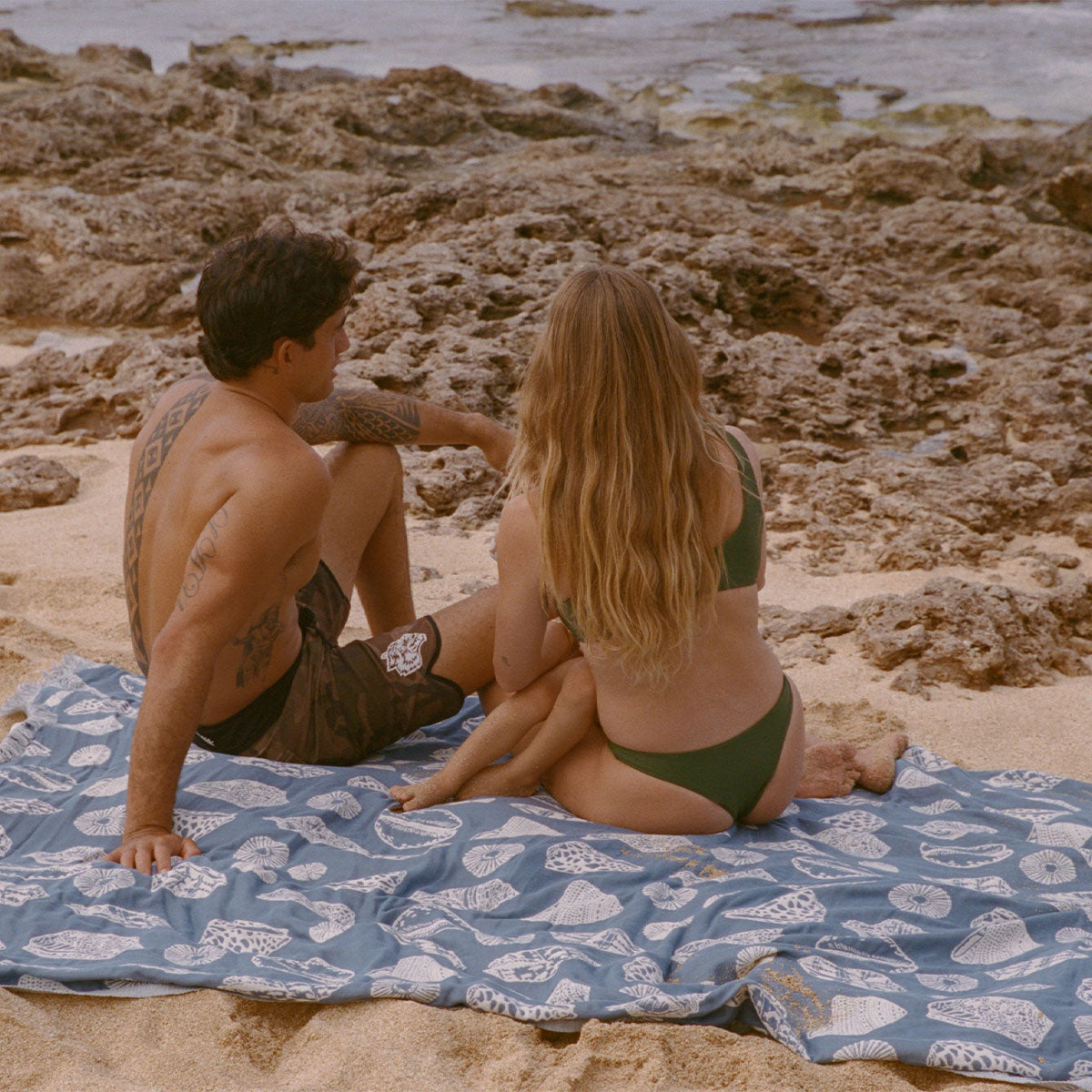 Cotton gauze blanket with sheer texture on a rocky beach near the ocean.