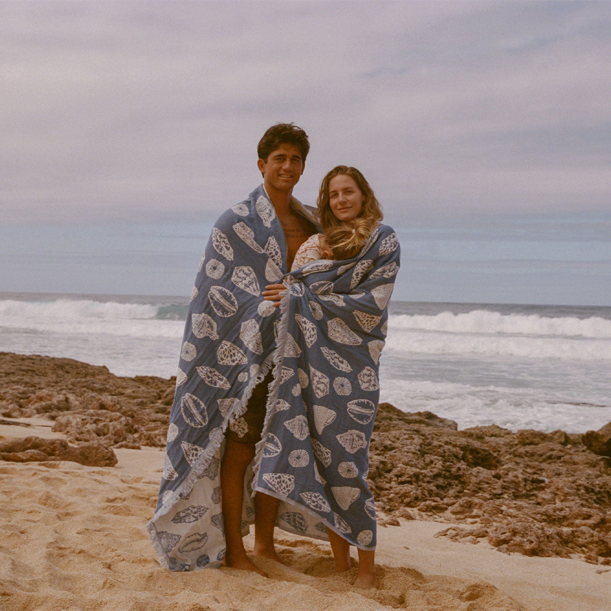 Blue oversized blanket, cozy fleece, outdoor beach setting.