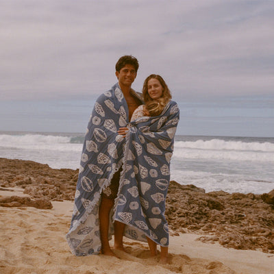 Blue oversized blanket, cozy fleece, outdoor beach setting.