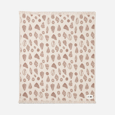 Oversized beige blanket with brown seashell print and fringe edges.