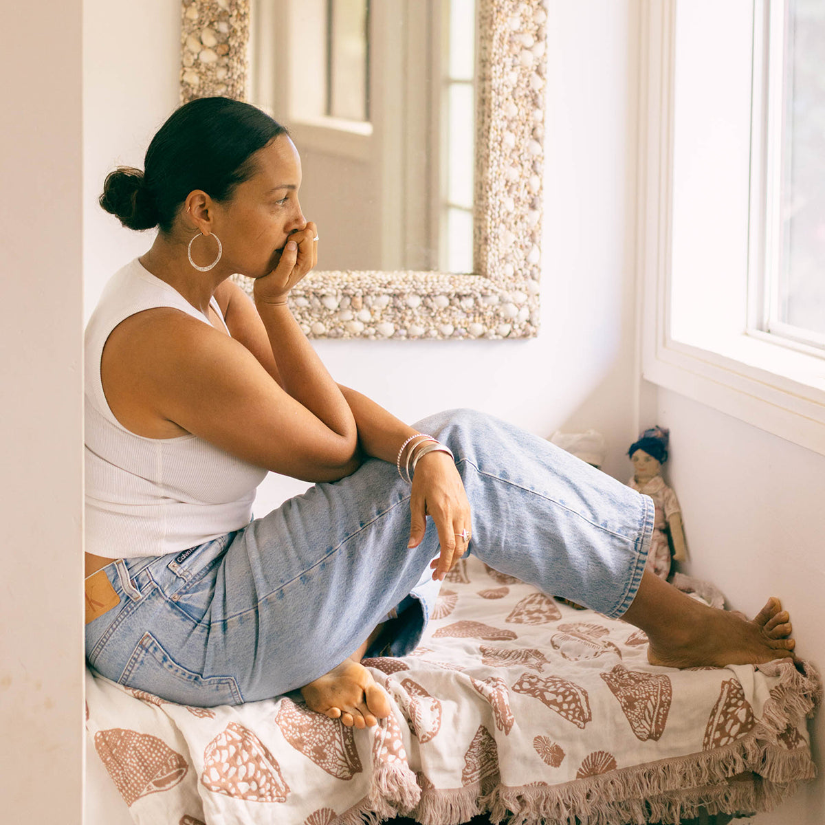 Ribbed tank top and light wash denim jeans folded on a gauzy cotton blanket.
