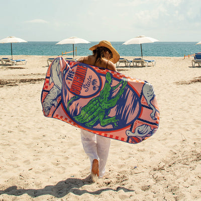 Travel towel with vibrant colors displayed on sand at the beach.