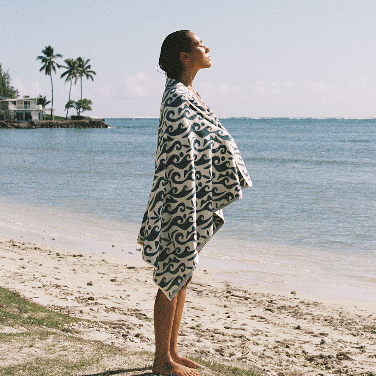 Beach towel with wave print on sand by the ocean.
