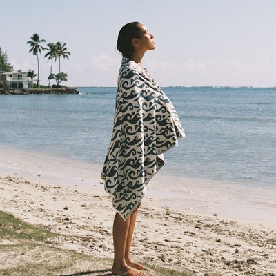 Beach towel with wave print on sand by the ocean.