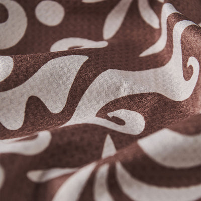 Sand resistant towel with white abstract and floral patterns, close-up of fabric texture.