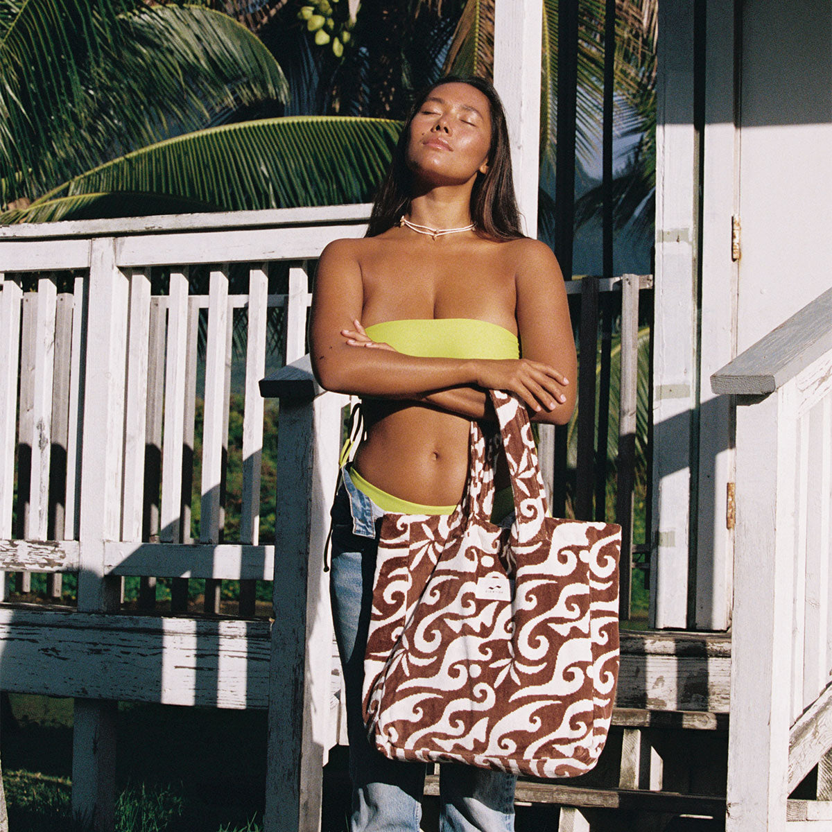 Yellow bikini top and patterned canvas tote bag with cotton lining on sunlit white porch.