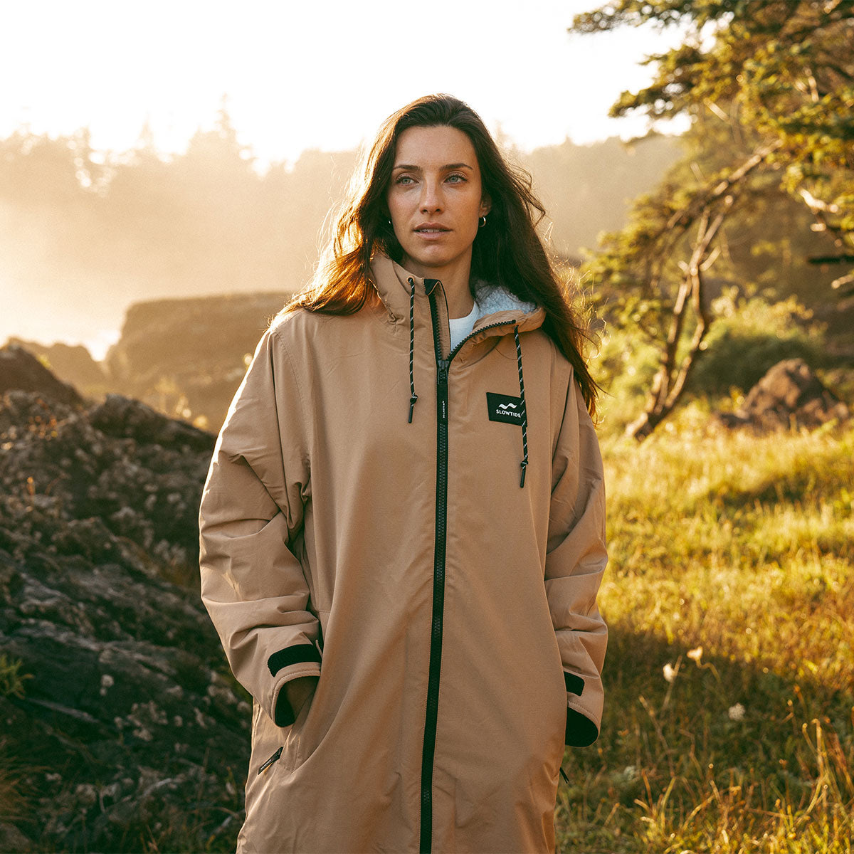 Tan all-weather parka with front pockets in outdoor setting.