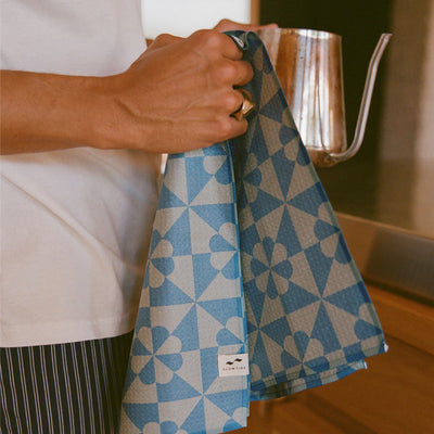 Patchwork cloth with blue quilt design and metal kettle on kitchen counter.